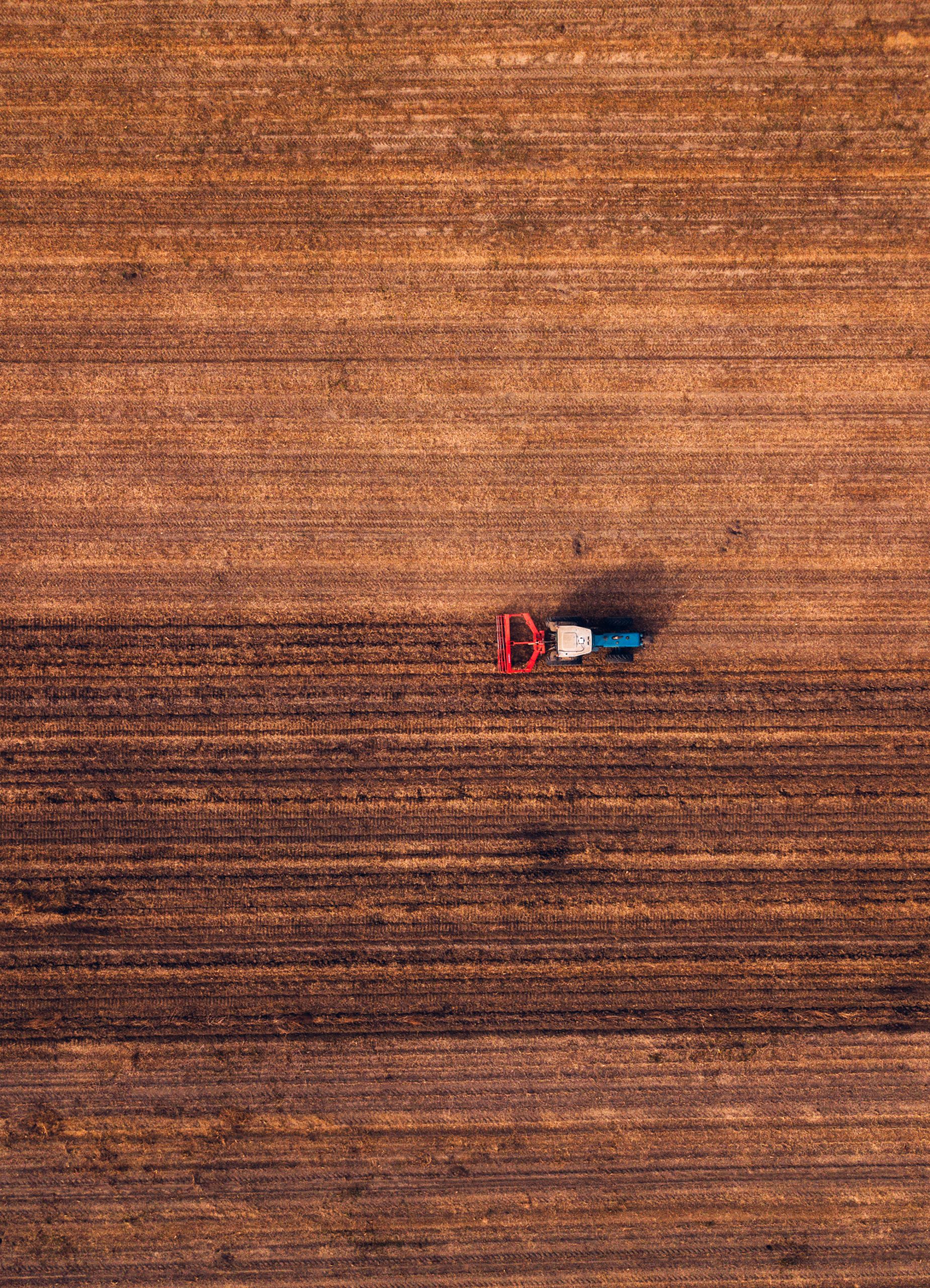 Aerial view of agricultural tractor doing stubble tillage in the field, top view from drone pov